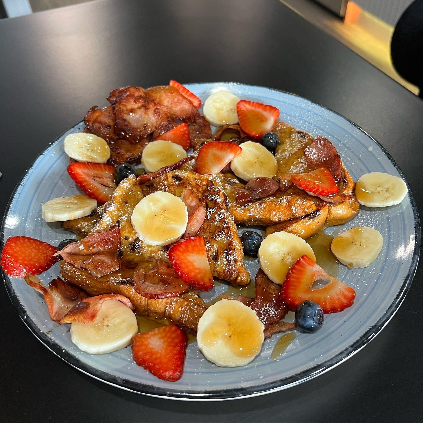 French toast with crispy bacon, banana and strawberries