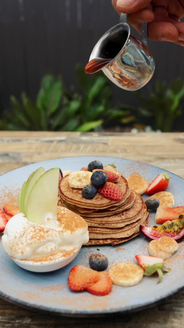 Maple syrup being poured over a pancake stack